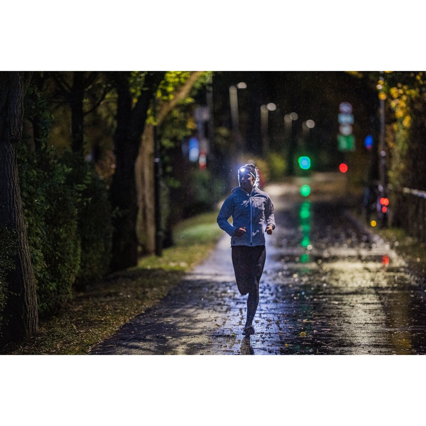 Coureur utilisant la Ledlenser NEO5R de nuit en ville sous la pluie
